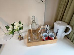 a wooden tray with a bottle and cups and a vase with flowers at Mount Eden Park in Auckland