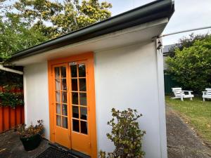 an orange door on a small white house at Mount Eden Park in Auckland