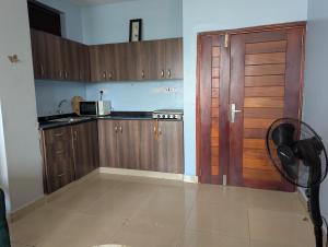 a kitchen with wooden cabinets and a door at Kampala suites Kisementi in Kampala
