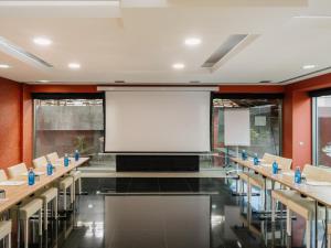 a conference room with tables and chairs and a large screen at MIM Sitges Member of Melia Collection in Sitges +43 photos