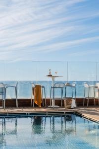 a swimming pool with chairs and a table and a table at MIM Sitges Member of Melia Collection in Sitges