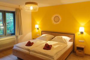 a yellow bedroom with a bed with two brown shoes at Ferienwohnung Feuer im Ferienhaus am Waldbach in Kirchzell