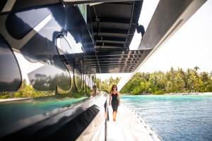 eine Frau, die auf einer Brücke über dem Wasser geht in der Unterkunft Solara Maldives Luxury Yacht Charter in Insel Filitheyo