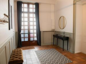 einen Flur mit einer Tür, einem Spiegel und einem Teppich in der Unterkunft La Maison De Famille in Luçon