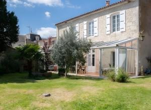 ein großes Backsteinhaus mit Terrasse und Garten in der Unterkunft La Maison De Famille in Luçon