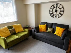 ein Wohnzimmer mit zwei Sofas und einer Uhr an der Wand in der Unterkunft 2 The Grove in Coalbrookdale