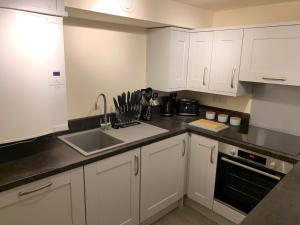 eine Küche mit weißen Schränken und einer Spüle in der Unterkunft 2 The Grove in Coalbrookdale