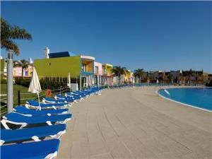 Eine Reihe von Strandstühlen mit Sonnenschirmen neben einem Pool in der Unterkunft Charming Orada 2-Bedroom Albufeira Duplex Apartment with Shared Pool sleeps 6 in Páteo