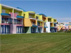 ein farbenfrohes Gebäude mit einem Feld davor in der Unterkunft Charming Orada 2-Bedroom Albufeira Duplex Apartment with Shared Pool sleeps 6 in Páteo