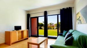 ein Wohnzimmer mit einem grünen Sofa und einem großen Fenster in der Unterkunft Charming Orada 2-Bedroom Albufeira Duplex Apartment with Shared Pool sleeps 6 in Páteo
