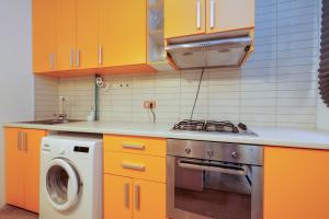 a kitchen with orange cabinets and a washing machine at By the Park in Văleni