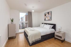 a white bedroom with a large bed and a window at Orchard by UTDM in Bristol