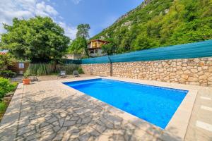 a swimming pool in front of a stone wall at KUCA MARSSILI in Grižane