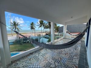 eine Hängematte in einem Zimmer mit Blick auf den Strand in der Unterkunft Casa vista Mar, pé na areia com piscina ! in Pitimbu