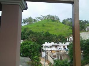 a view of a green hill from a window at Akshaya Guest Inn Kandy in Kandy