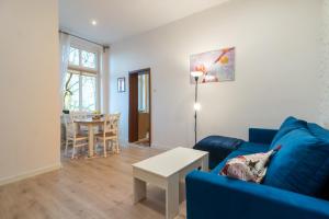 ein Wohnzimmer mit einem blauen Sofa und einem Tisch in der Unterkunft Mysłowice Urban Harmony Apartment by BookingHost in Mysłowice