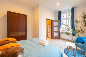 ein Schlafzimmer mit einem Bett, einem Stuhl und einem Fenster in der Unterkunft Mysłowice Urban Harmony Apartment by BookingHost in Mysłowice
