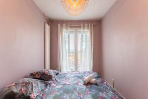 Schlafzimmer mit einem Bett, einem Fenster und einem Kronleuchter in der Unterkunft Le 12 - City Center in Colmar