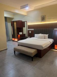 a bedroom with a bed and a bench in it at Nippon Grand Hotel and Apartment in Abuja