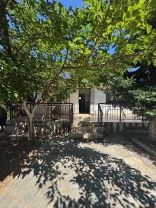 ein Baum vor einem Gebäude mit einem Zaun in der Unterkunft claudistaudis guesthouse in Vergia