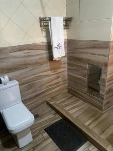 a bathroom with a toilet and a shower with wooden walls at Nippon Grand Hotel and Apartment in Abuja +11 photos
