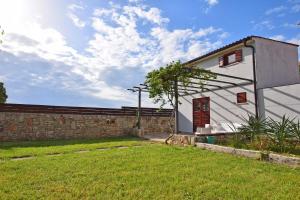 a white house with a stone wall and a yard at Villa San Rocco with heated pool in Vodnjan