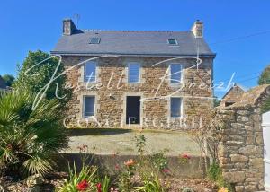 ein altes Backsteinhaus mit einem Schild darauf in der Unterkunft Chez Jeanne, maison en pierre de pays avec jardin in Plougonver