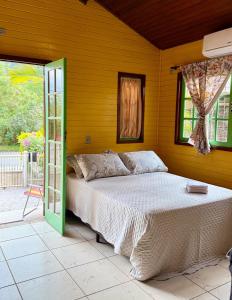 a bedroom with a bed with a green door at Casinha Encantada-Café Cacupé Hospedagem in Florianópolis
