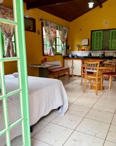 a bedroom with a bed and a table and a kitchen at Casinha Encantada-Café Cacupé Hospedagem in Florianópolis