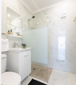 une salle de bain blanche avec douche et toilettes dans l'établissement TelMar SeaView, à Oroklini