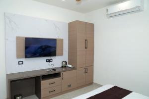 ein Schlafzimmer mit einem Fernseher an einer weißen Wand in der Unterkunft Den Inn in Hisār