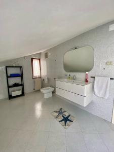 een badkamer met een wastafel, een toilet en een spiegel bij Casa Roberto in Giulianova
