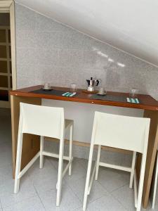 twee witte stoelen aan een tafel met een toonbank bij Casa Roberto in Giulianova