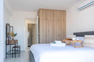 - une chambre avec un grand lit blanc et une armoire en bois dans l'établissement TelMar SeaView, à Oroklini