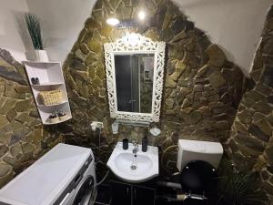 a stone bathroom with a sink and a mirror at Miri Apartament in Lupeni +21 photos