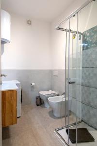 a bathroom with a toilet and a glass shower at MagliaNeraApartment in Quartu Sant'Elena