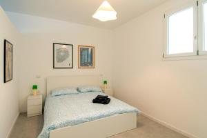 a white bedroom with a bed and a window at MagliaNeraApartment in Quartu Sant'Elena