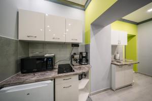a kitchen with white cabinets and a black microwave at White House Apartman Miskolc, Green Room in Miskolc