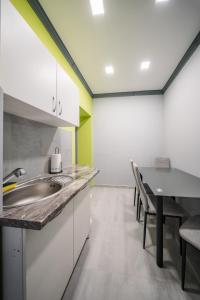 a kitchen with a sink and a table with chairs at White House Apartman Miskolc, Green Room in Miskolc