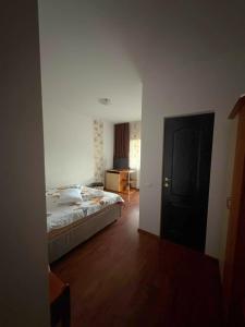 ein Schlafzimmer mit einem Bett in einem Zimmer mit Holzboden in der Unterkunft Pensiunea Tora in Vatra Dornei