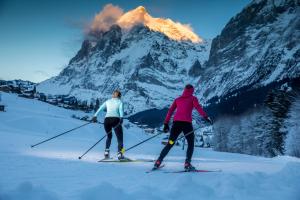 two people on skis in front of a mountain at Hotel Victoria Lauberhorn Wengen, a Faern Collection Hotel in Wengen