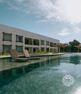 einem Pool mit zwei Stühlen vor einem Gebäude in der Unterkunft Ocean Pipa in Pipa