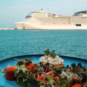 a plate of food with a cruise ship in the background at Mina Hotel and Residences By The Torch in Doha