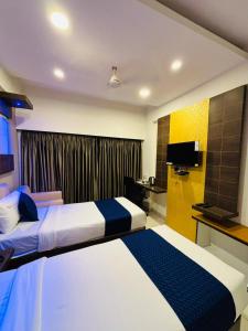 a hotel room with two beds and a television at Hotel Sandalwood Inn - Rooms and Spa in Bengaluru