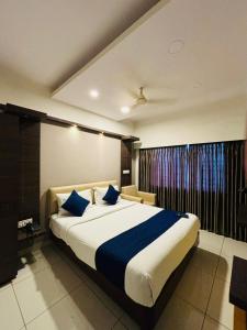 a bedroom with a large bed with blue pillows at Hotel Sandalwood Inn - Rooms and Spa in Bengaluru