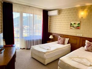 une chambre d'hôtel avec deux lits, un bureau et une fenêtre dans l'établissement Хотел Елит Релакс, à Devin