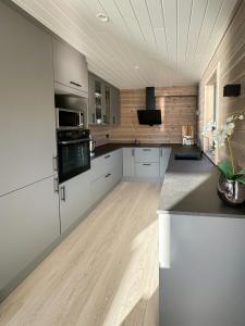 eine große Küche mit weißen Schränken und Holzböden in der Unterkunft Panoramic Cabin By Lake Lundevannet in Tjellesvik