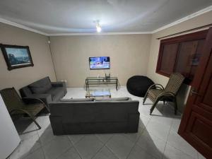 a living room with a couch and chairs and a tv at Medeiros in Capão da Canoa