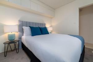 une chambre avec un grand lit blanc avec des oreillers bleus dans l'établissement Cosy and convenient leafy apartment, à Majura