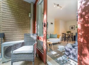 - une terrasse couverte avec des chaises, un canapé et une table dans l'établissement Cosy and convenient leafy apartment, à Majura